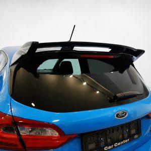 Rear view of a blue Ford hatchback with a dark rear window and roof spoiler in a studio setting