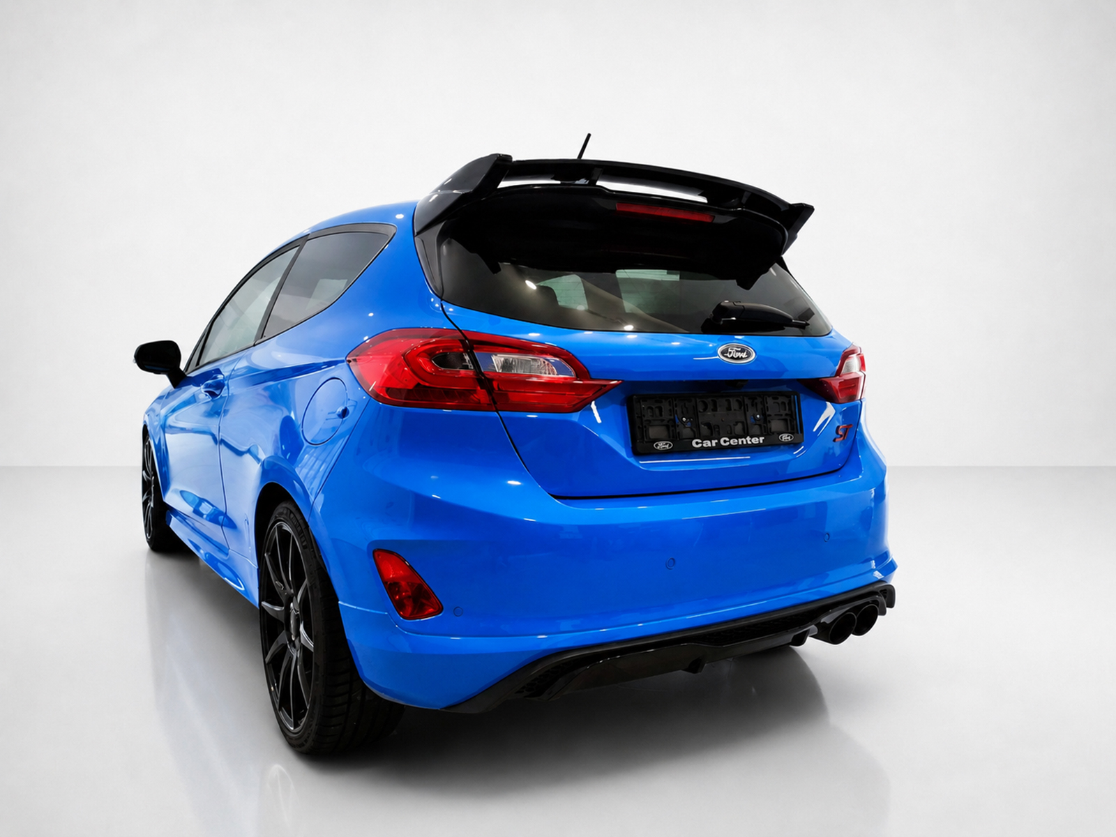 A-542_2jpg - OPSHOLDERS Blue Ford hatchback viewed from the rear in a white studio, showing a spoiler and red tail lights.
