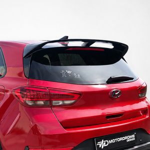 Rear view of a red hatchback with a large black spoiler and tailgate decals visible through the rear window.