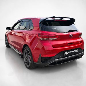 Red hatchback SUV shown from the rear-right, featuring a black rear bumper, large spoiler, and aftermarket wheels with a Motordrome Design plate.