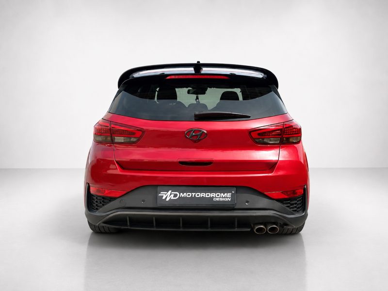 Red Hyundai hatchback rear view in a studio setting with a black spoiler and dual exhausts. Plate reads 'MotorDrome Design'.