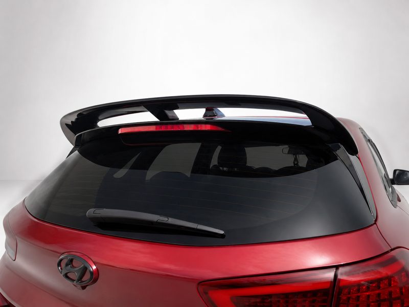 Red Hyundai hatchback rear with a large spoiler and high-mounted brake light above the rear window.