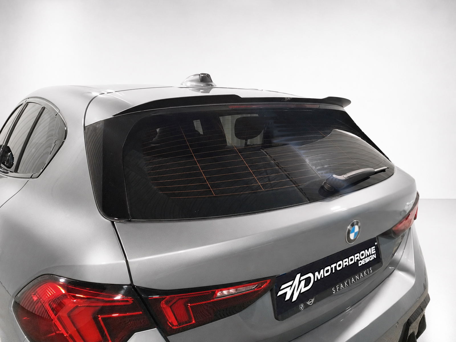 A-546_1jpg - OPSHOLDERS Rear three-quarter view of a silver BMW SUV, showing taillights, rear hatch, and a rear wiper (showroom setup).