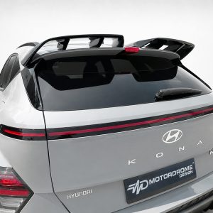 Rear view of a silver Hyundai SUV with a full-width taillight strip, roof spoiler, and Hyundai emblem visible in a studio setting, Kona model name shown on the back.