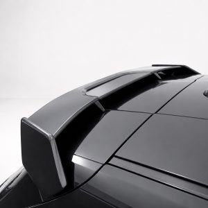 Close-up of a glossy black car roof with a rear spoiler against a light background, highlighting its aerodynamics.