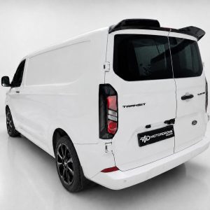 Rear-three-quarter view of a white Ford Transit cargo van with black wheels in a studio setting.