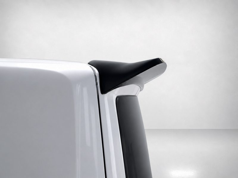 Close-up of a black car spoiler mounted on a silver trunk, elevating the rear edge of the vehicle.