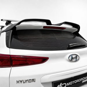 White Hyundai SUV shown from the rear with a roof rack, spoiler, and red taillights; Hyundai badge visible on the tailgate.