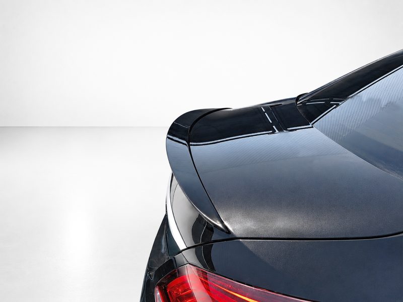 Close-up of a dark, glossy car rear with a red taillight.