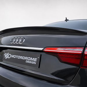 Rear view of a black Audi A4 showing the Audi rings, glossy finish, and red taillights with an MD Motordrome Design plate in the foreground