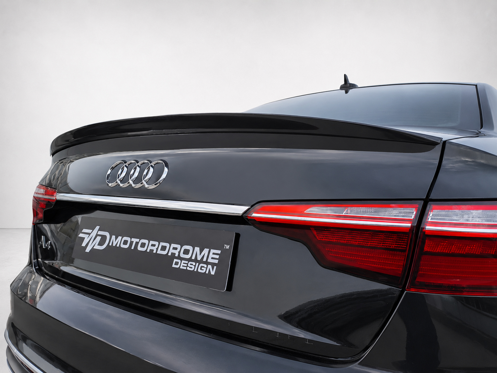 A-556_1jpg - OPSHOLDERS Rear view of a black Audi A4 showing the Audi rings, glossy finish, and red taillights with an MD Motordrome Design plate in the foreground