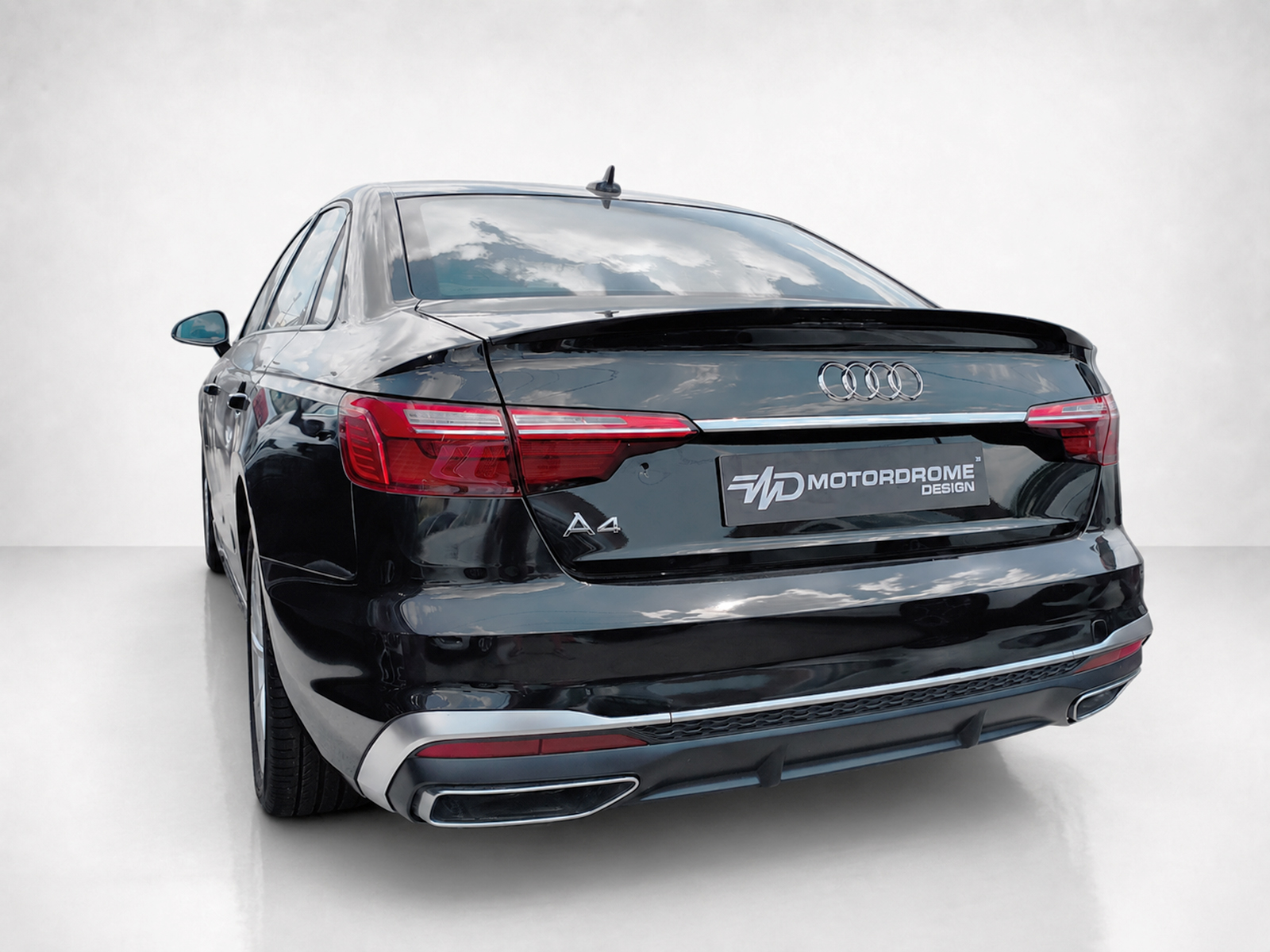 A-556_2jpg - OPSHOLDERS Rear view of a black Audi A4 in a studio setting with visible logo and taillights, plate readable as MOTORDROME DESIGN.