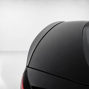 A-556_4jpg - OPSHOLDERS Close-up of the rear section of a glossy black car, featuring curved trunk lines and a red taillight on the left edge