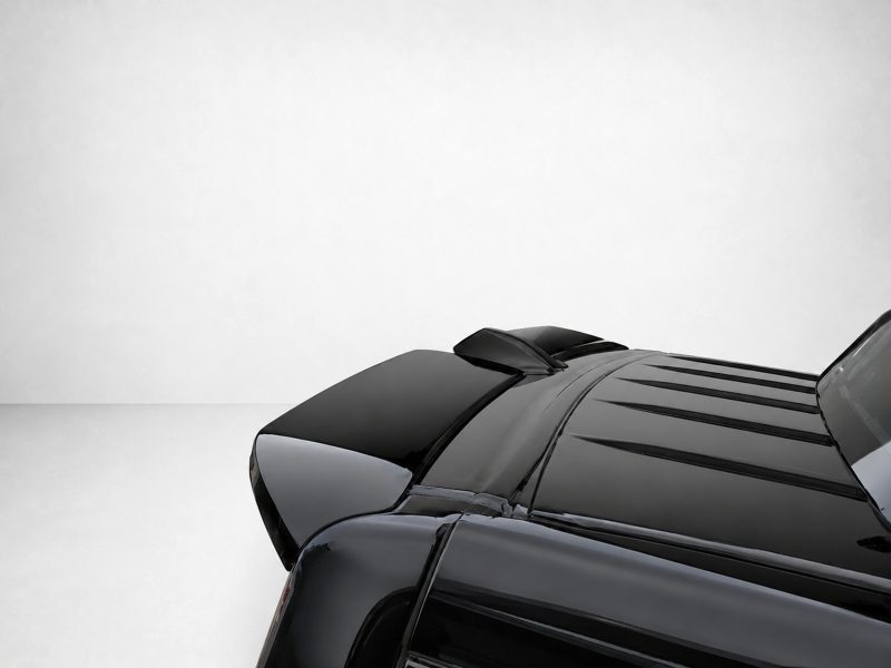 Partial view of a sleek black car, focusing on the glossy hood and roof at the lower-right corner.