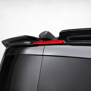 Rear view of a glossy black SUV: slim red LED brake light integrated into the roof spoiler with a small camera beneath it.