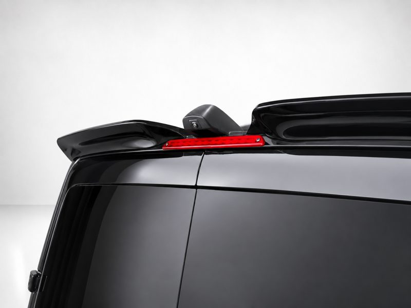 Rear view of a glossy black SUV: slim red LED brake light integrated into the roof spoiler with a small camera beneath it.