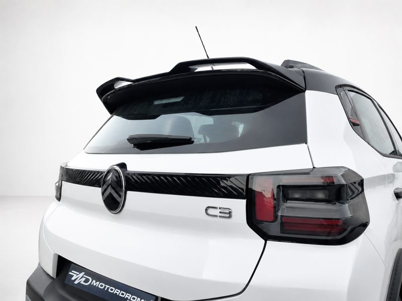 Rear view of a white SUV with a black roof spoiler, showing a 'C3' badge on the tailgate and dark taillights in a studio setting.