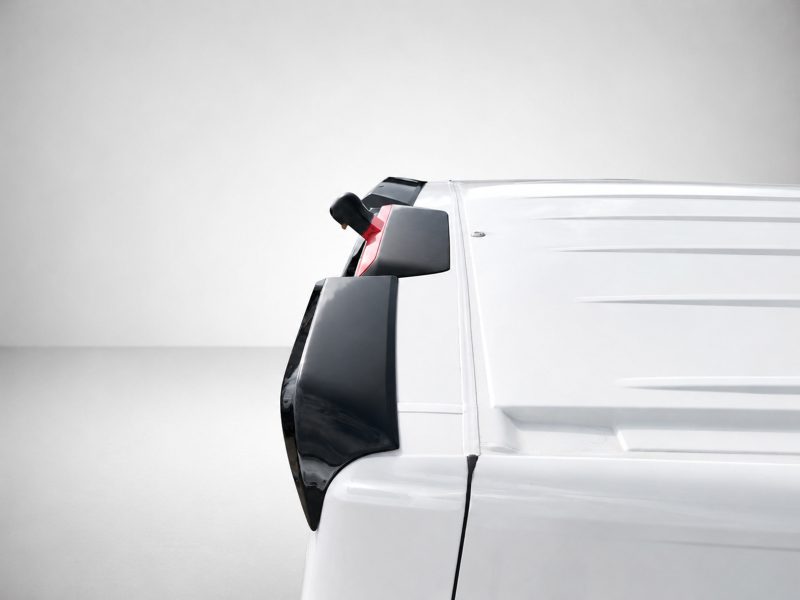 A-561_5jpg - OPSHOLDERS Partial side view of a white cargo van with black trim and mirror, shown against a neutral background