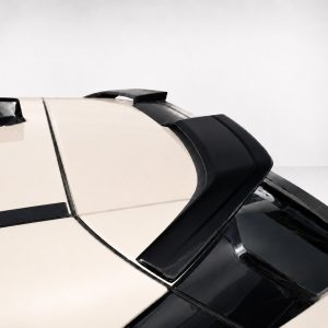 Close-up of a cream-colored car hood with black aerodynamic vents and trim, photographed from a low angle against a pale background.