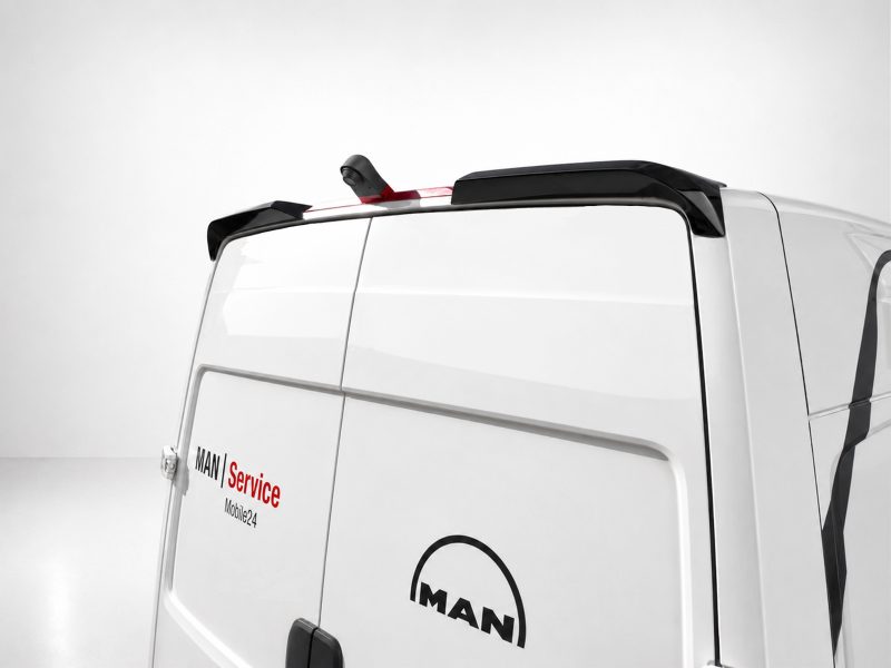 A-563_4jpg - OPSHOLDERS Rear corner of a white MAN van with 'MAN Service Mobile24' branding and a black roof spoiler/antenna on top.