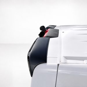 A-563_5jpg - OPSHOLDERS Close-up of a white truck cab's front corner, showing the black side mirror housing and door handle.