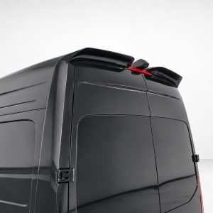Close-up of the rear corner of a glossy black van, showing the roof spoiler and taillight area.