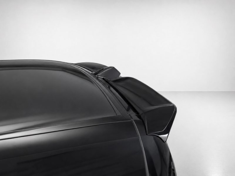 Rear spoiler on a black sports car, close-up against a light gray background