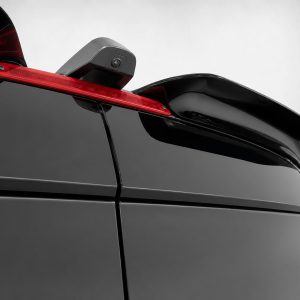 Close-up of a glossy black car rear with a red third brake light and a mounted camera on the spoiler.