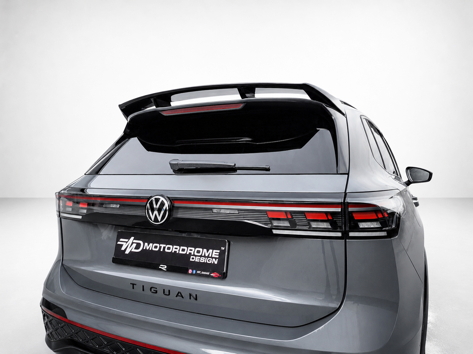 A-565_1jpg - OPSHOLDERS Rear view of a gray Volkswagen Tiguan with a custom Motordrome Design license plate and integrated tail lights under a spoiler