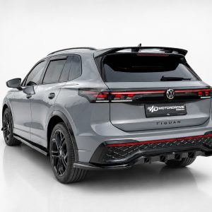 A-565_2jpg - OPSHOLDERS Rear three-quarter view of a gray Volkswagen Tiguan SUV in a studio setting with black alloy wheels and roof railsedicailed by a white backdrop.