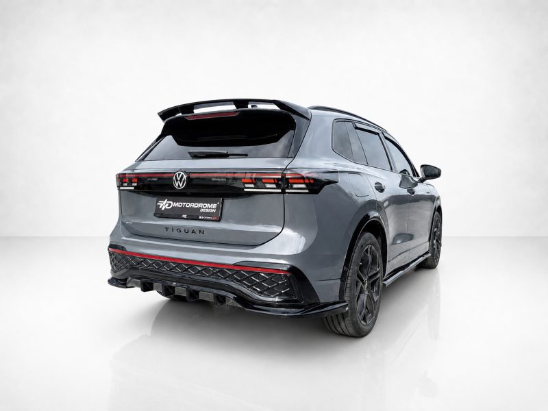 A-565_4jpg - OPSHOLDERS Rear view of a metallic gray Volkswagen Tiguan with a sports body kit and red taillight strip in a studio setting.