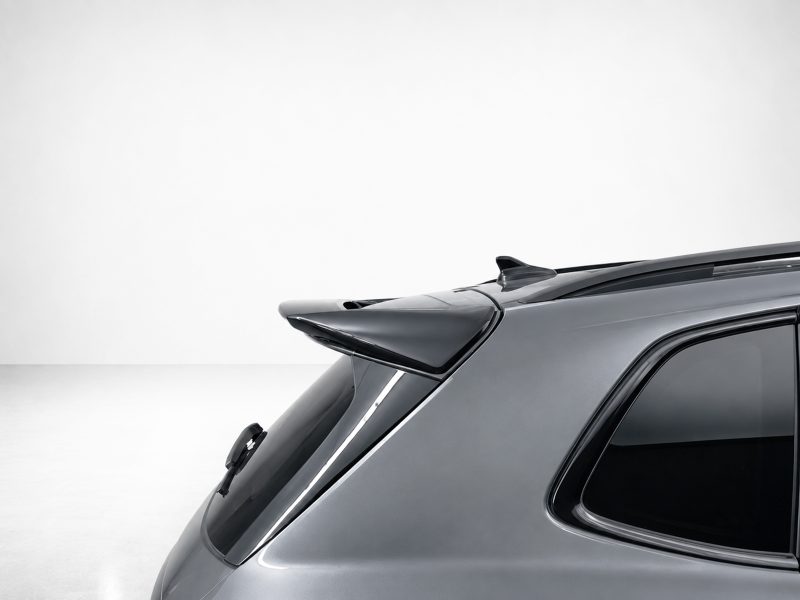 A-565_6jpg - OPSHOLDERS Rear-side view of a gray car hatchback with a prominent spoiler and curved rear window.