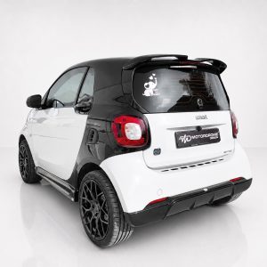 Two-tone white and black Smart car shown from the rear-left side with large black alloy wheels and custom decals on the back window (Motordrome Design).