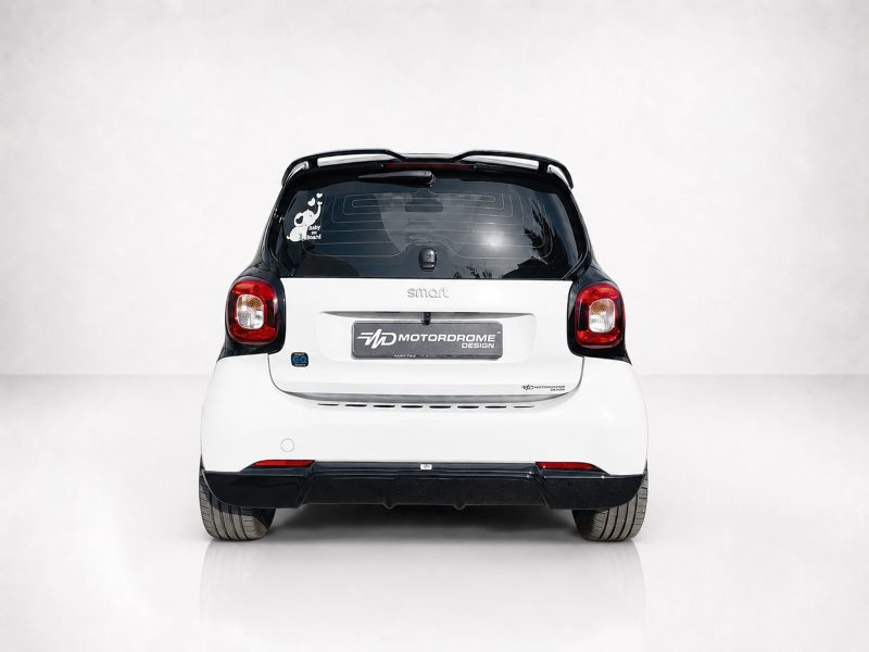 Rear view of a white Smart car with a black roof, taillights lit, and a center badge reading 'smart'.