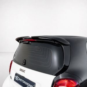 Rear view of a two-tone hatchback showing a rear spoiler, wiper, and curved red taillights against a light studio backdrop.