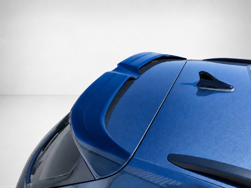 Close-up of a blue car roof showing a shark-fin antenna and rear spoiler at an angle