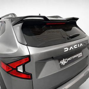 Rear three-quarter view of a silver SUV with a roof spoiler, rear wiper, and red taillights labeled DACIA.