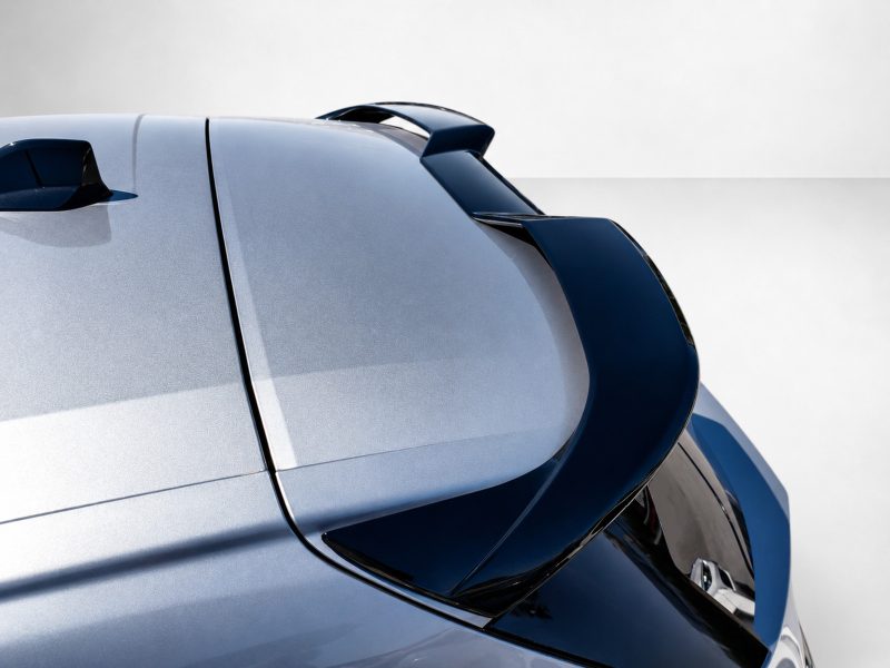 A-574_4jpg - OPSHOLDERS Close-up of a silver-blue sports car rear with a dark blue aerodynamic spoiler against a light background, emphasizing design details.