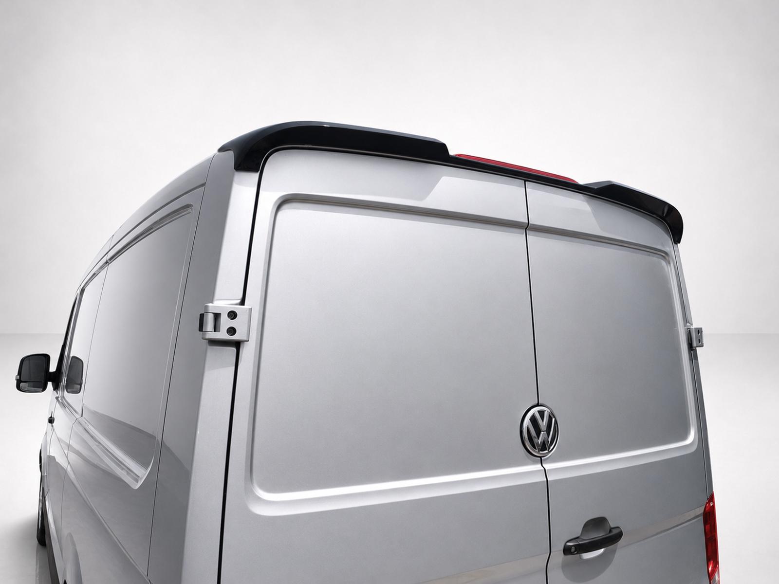 A-575_1jpg - OPSHOLDERS Rear view of a silver VW cargo van with closed double doors and a small roof spoiler on top edge of the doors, VW logo visible