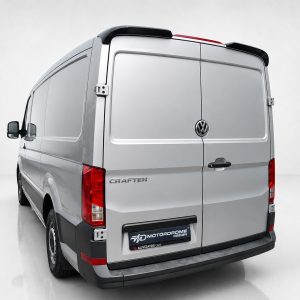 A-576_2jpg - OPSHOLDERS Rear view of a silver Volkswagen Crafter cargo van with dual doors and prominent VW emblem in a studio setting, showing red taillights and plastic bumper.