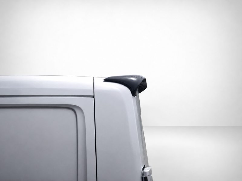 A-576_5jpg - OPSHOLDERS Light gray van's rear corner with a black roof spoiler or spoiler-like accessory on the top edge. It highlights the tail end of the vehicle.