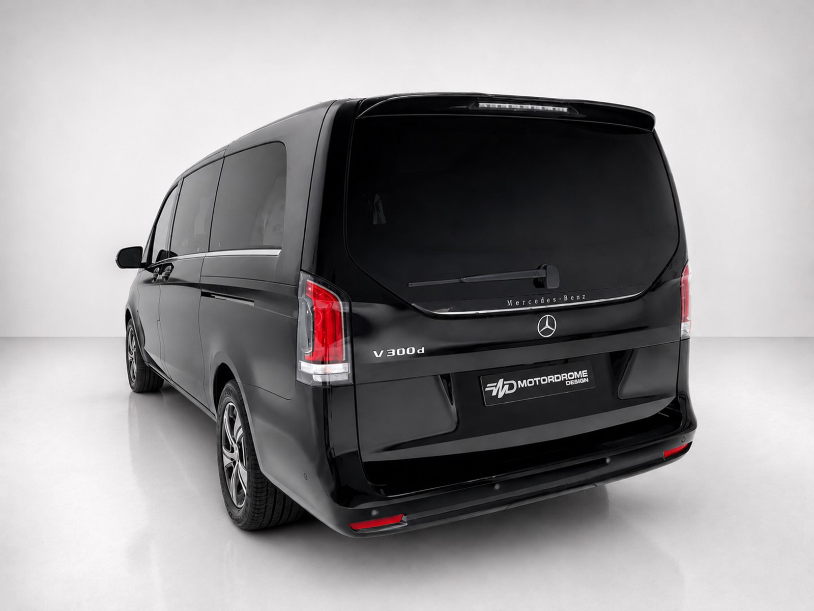 A-578_2jpg - OPSHOLDERS Rear view of a black Mercedes-Benz V 300d van in a white studio setting, showing taillights and rear window.