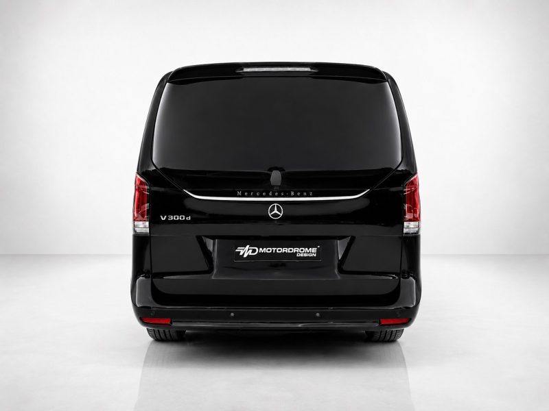 A-578_3jpg - OPSHOLDERS Rear view of a glossy black Mercedes-Benz V300d van in a studio setting, with Mercedes logo and V300d badge visible underlit tailgate light strip.