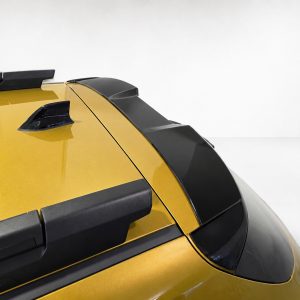 A-579_4jpg - OPSHOLDERS Close-up of the rear roof area of a yellow car, showing a roof rack, black spoiler, and antenna fin against a light background.