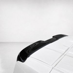 Rear portion of a white car with a black roof spoiler against a gray backdrop.