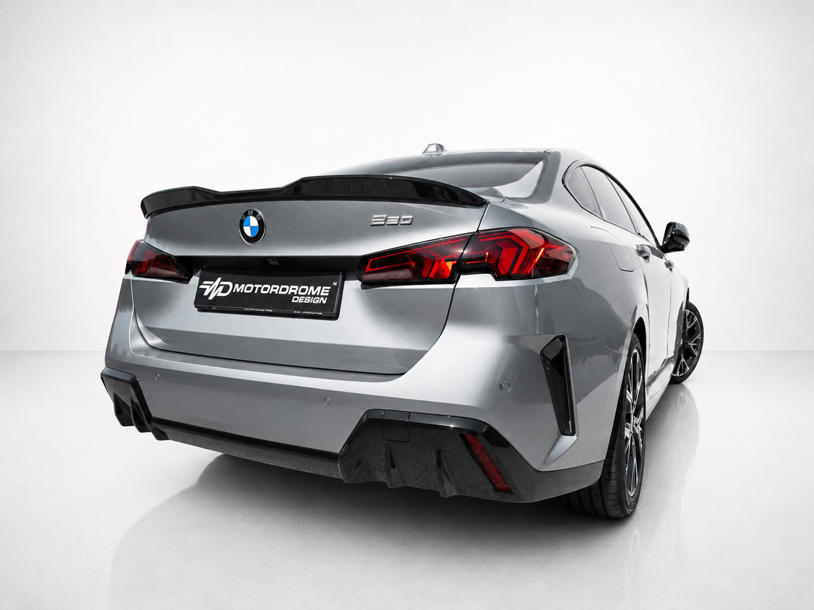 A-581_1jpg - OPSHOLDERS Silver BMW 220 rear view in a studio setting with a Motordrome Design license plate and red taillights
