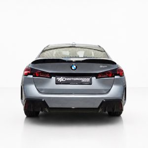 A-581_2jpg - OPSHOLDERS Rear view of a silver BMW 520d sedan in a bright studio, taillights visible and MD MotorDrome plate center.