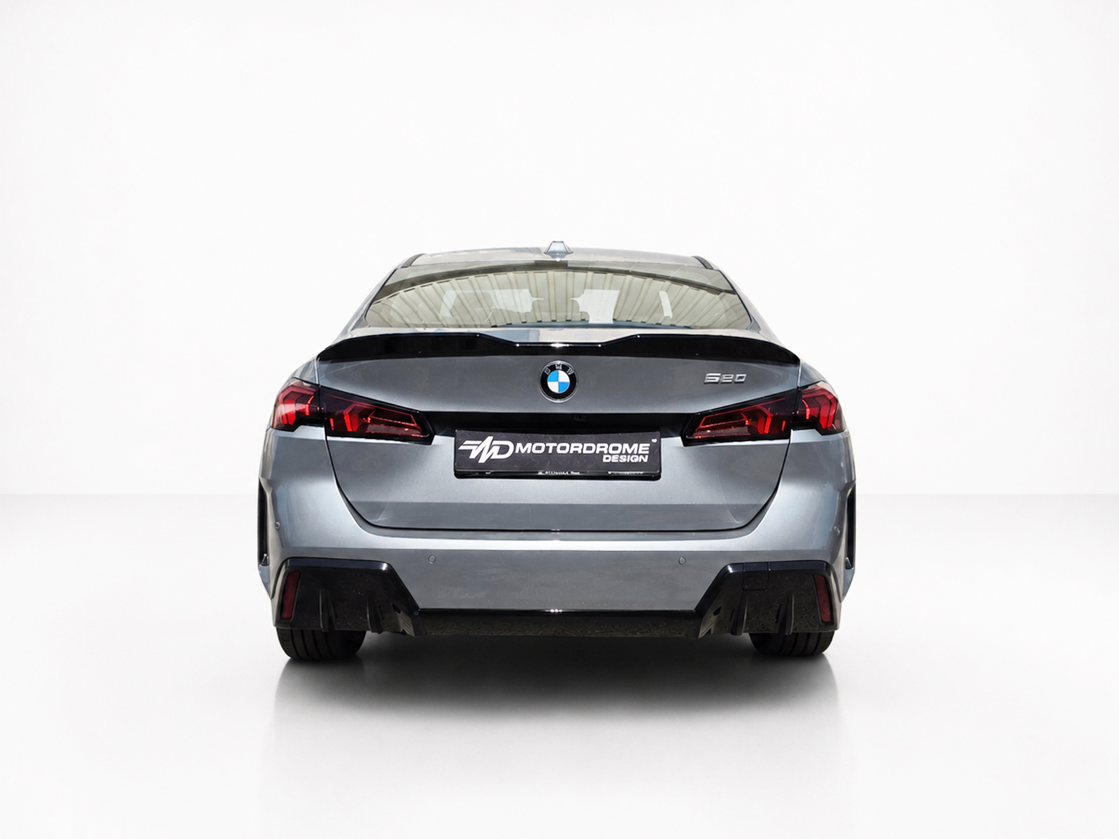 A-581_2jpg - OPSHOLDERS Rear view of a silver BMW 520d sedan in a bright studio, taillights visible and MD MotorDrome plate center.