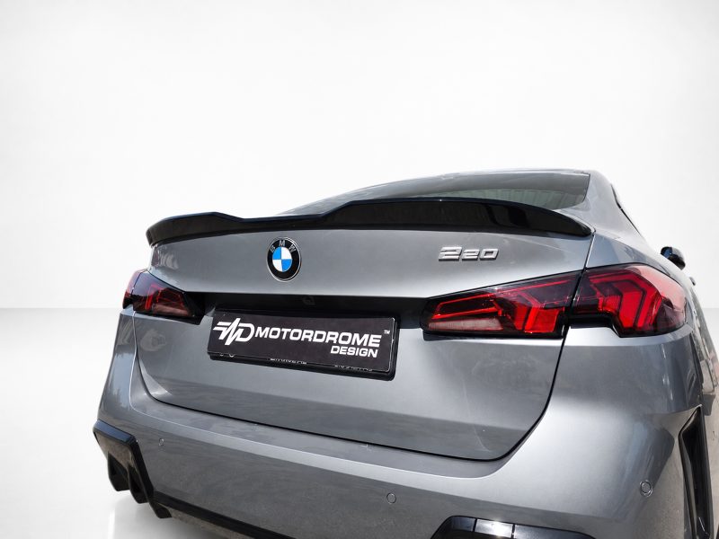 A-581_5jpg - OPSHOLDERS Rear of a silver BMW 320 with a black spoiler and red taillights, displaying a MD Motordrome Design plate