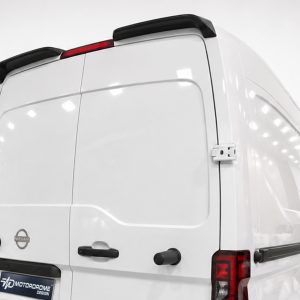 Rear view of a white cargo van with black roof rails and rear doors, Nissan badge visible on the left door.